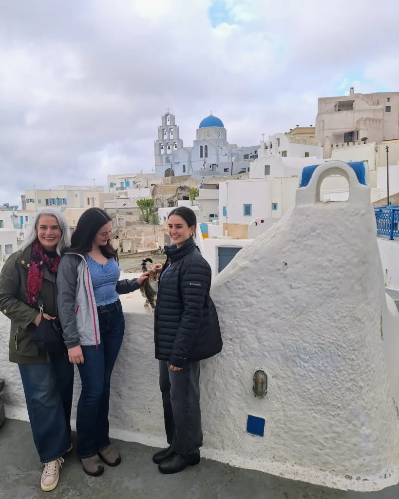 A sweet family moment in Pyrgos with a mother and her two daughters petting a tabby cat during the off-season