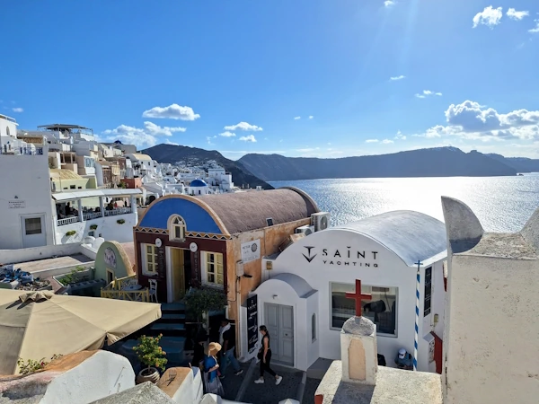 Why Santorini feels tiring: sunny Oia streets with stairs, walking paths, and caldera views showing energy and movement
