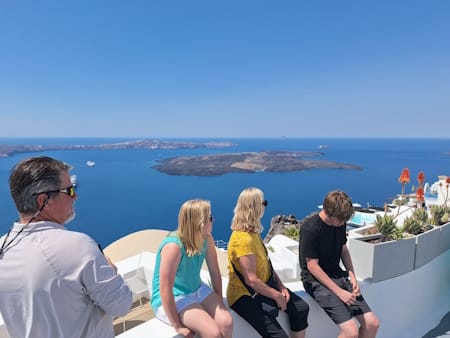 an image of a family watching the caldera views in imerovigli, visibly tired: exploring santorini can feel tiring from sheer sensory overload