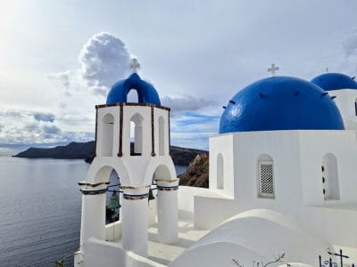 Santorini famous blue dome overlooking the caldera in soft morning light, before the crowds arrive