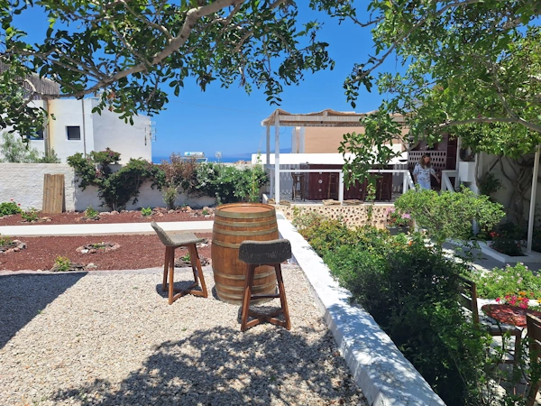 Garden courtyard at Domus K 1885 in Oia, Santorini, featuring relaxed seating, volcanic stone details, and a slower atmosphere away from crowded pathways.