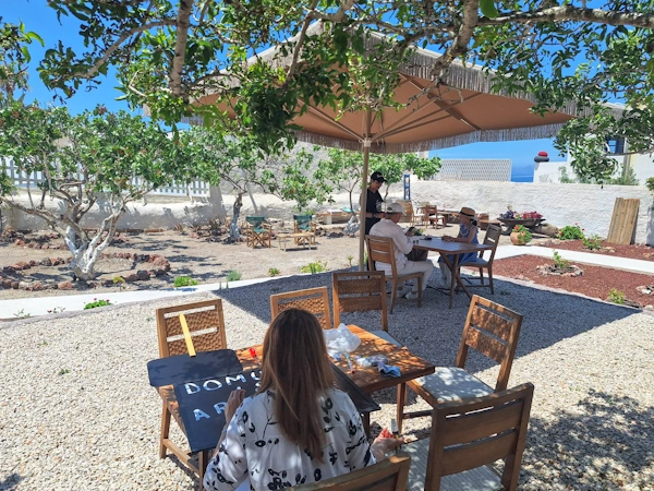 Guests enjoying wine and soft drinks  in the garden of Domus K 1885, a restored captain’s house in the heart of Oia, Santorini. Children welcome as well as grown-ups.